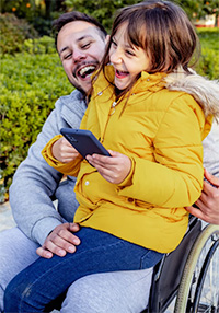 Father in wheelchair laughing with daughter